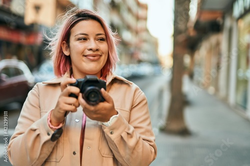 Young hispanic girl smiling happy using reflex camera at the city. © Krakenimages.com