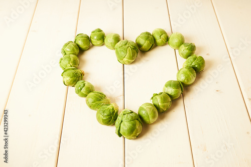 Bunch of fresh raw Brussel sprouts in heart shape on a white wood table