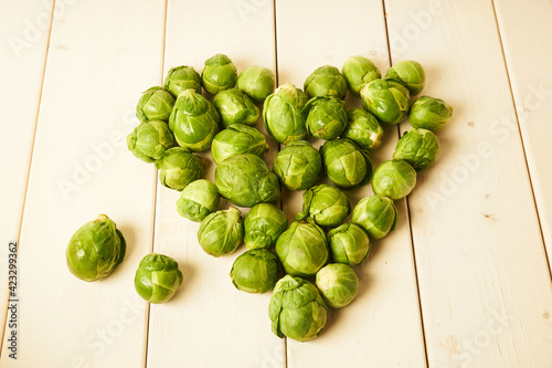 Bunch of fresh raw Brussel sprouts in heart shape on a white wood table