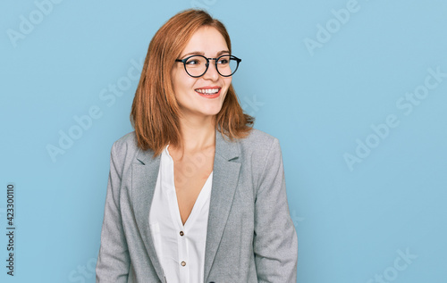 Fotografie Young caucasian woman wearing business style and glasses looking away to side with smile on face, natural expression