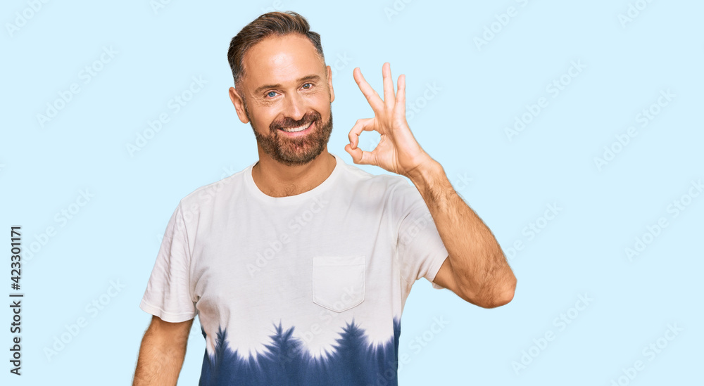 Handsome middle age man wearing casual tie dye tshirt smiling positive doing ok sign with hand and fingers. successful expression. Handsome middle age man wearing casual tie dye tshirt smiling positive doing ok sign with hand and fingers. successful expression.