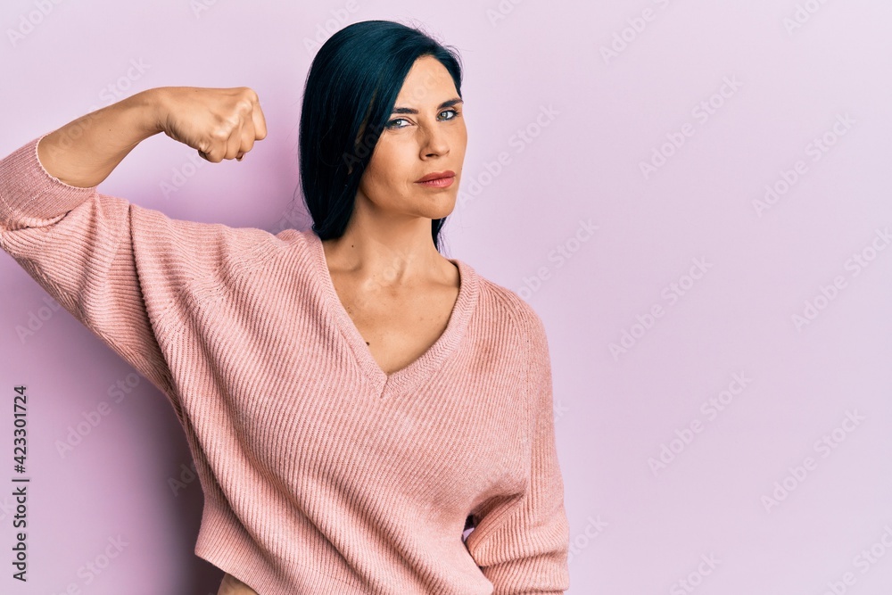Fototapeta premium Young caucasian woman wearing casual clothes strong person showing arm muscle, confident and proud of power