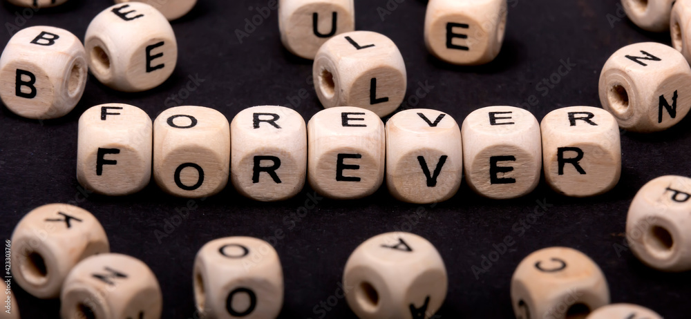 The word FOREVER on wooden cubes around cubes with letters The word FOREVER on wooden cubes around cubes with letters