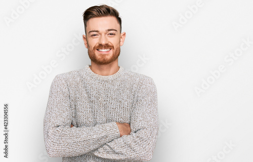 Young redhead man wearing casual winter sweater happy face smiling with crossed arms looking at the camera. positive person.