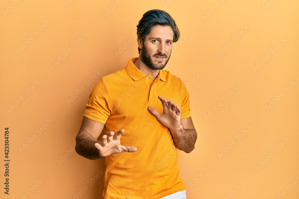 Young hispanic man wearing casual yellow t shirt disgusted expression, displeased and fearful doing disgust face because aversion reaction. with hands raised Young hispanic man wearing casual yellow t shirt disgusted expression, displeased and fearful doing disgust face because aversion reaction. with hands raised