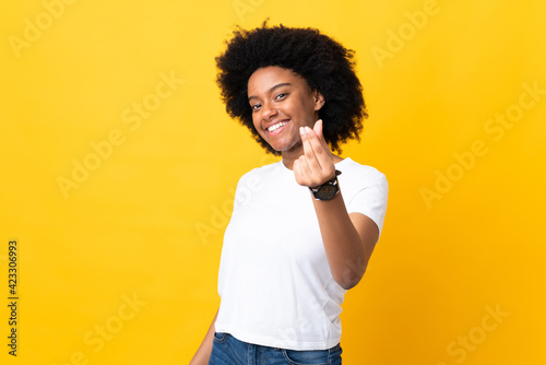 Young African American woman isolated on yellow background making money gesture photo