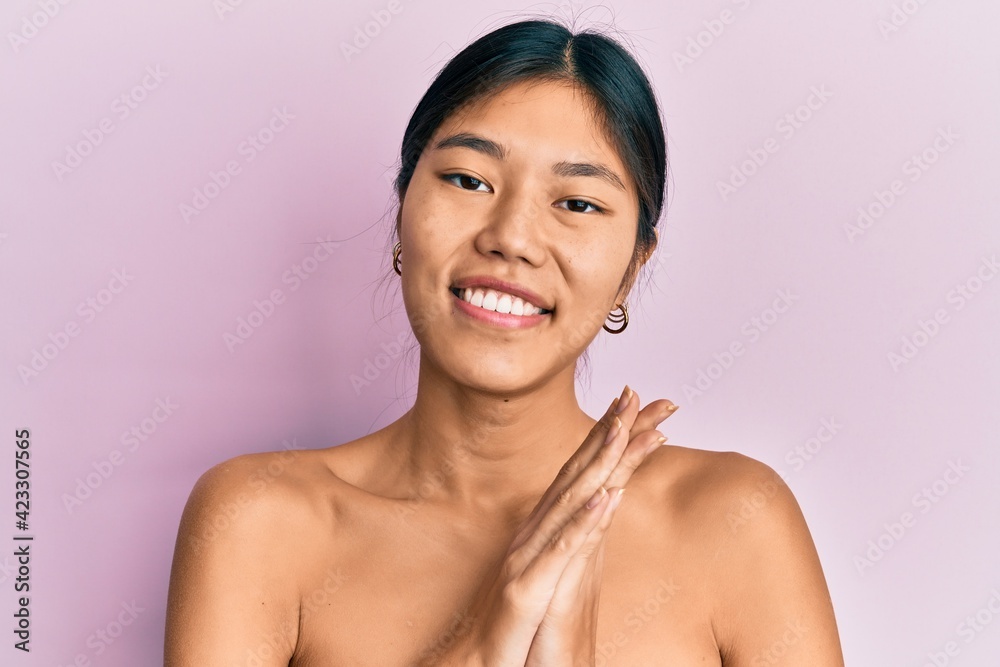 Young chinese woman standing topless showing skin praying with hands together asking for forgiveness smiling confident. Young chinese woman standing topless showing skin praying with hands together asking for forgiveness smiling confident.