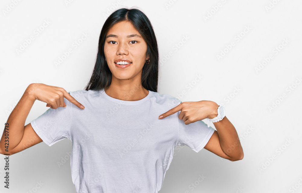 Beautiful young asian woman wearing casual white t shirt looking confident with smile on face, pointing oneself with fingers proud and happy. Beautiful young asian woman wearing casual white t shirt looking confident with smile on face, pointing oneself with fingers proud and happy.