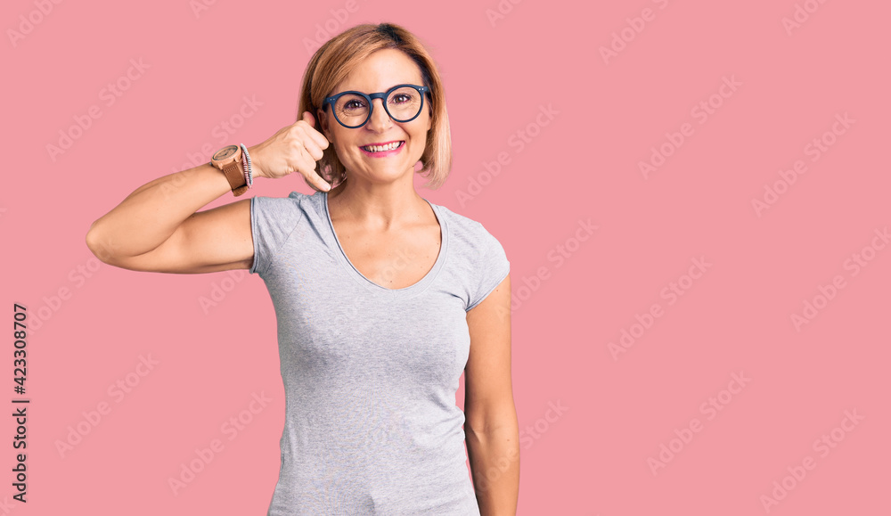 Young blonde woman wearing casual clothes smiling doing phone gesture with hand and fingers like talking on the telephone. communicating concepts.