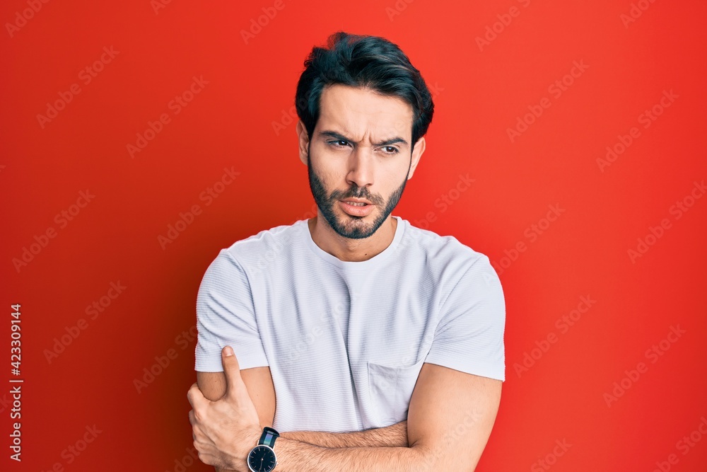 Young hispanic man wearing casual white tshirt shaking and freezing for winter cold with sad and shock expression on face Young hispanic man wearing casual white tshirt shaking and freezing for winter cold with sad and shock expression on face