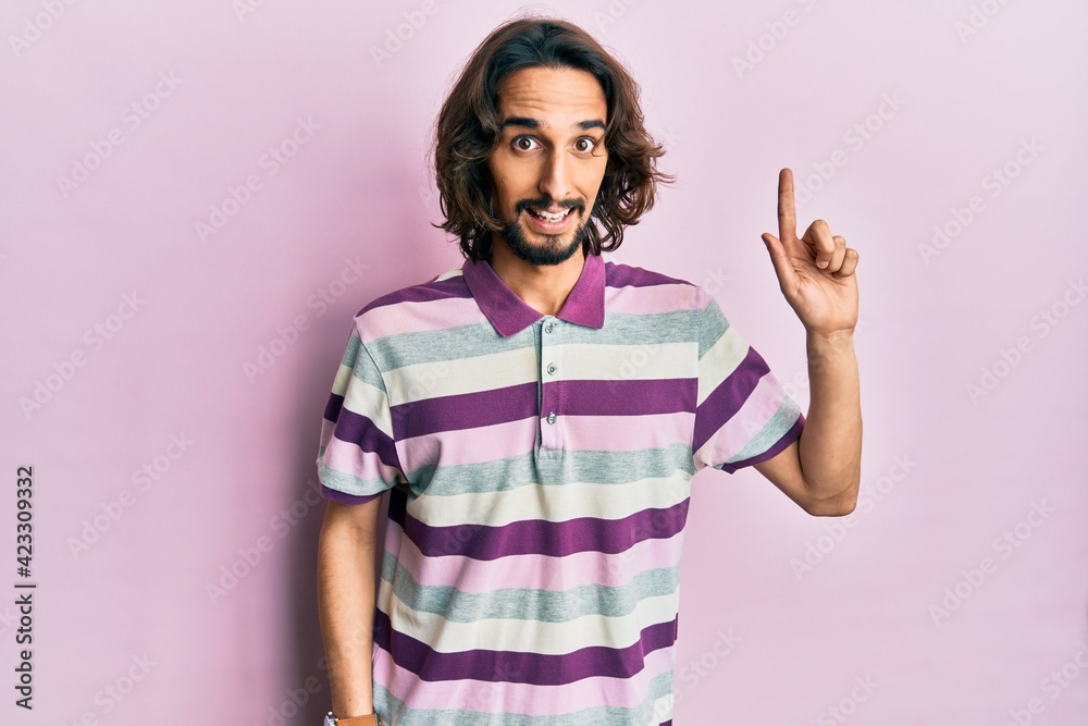 Young hispanic man wearing casual clothes smiling with an idea or question pointing finger up with happy face, number one Young hispanic man wearing casual clothes smiling with an idea or question pointing finger up with happy face, number one