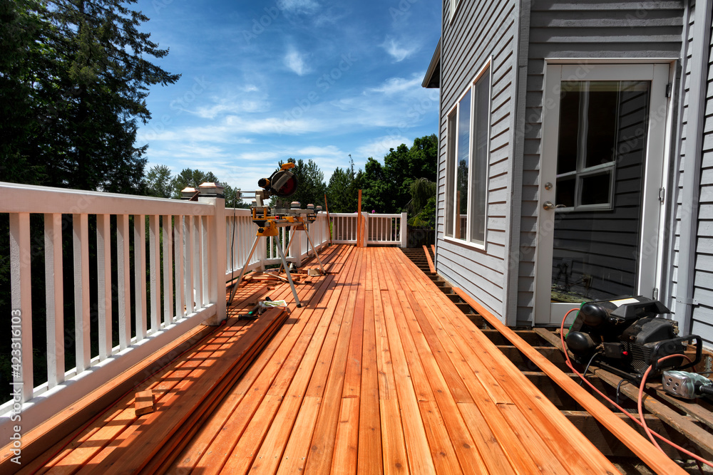 Complete home outdoor deck remodel with new red cedar wooden boards being installed - obrazy, fototapety, plakaty 