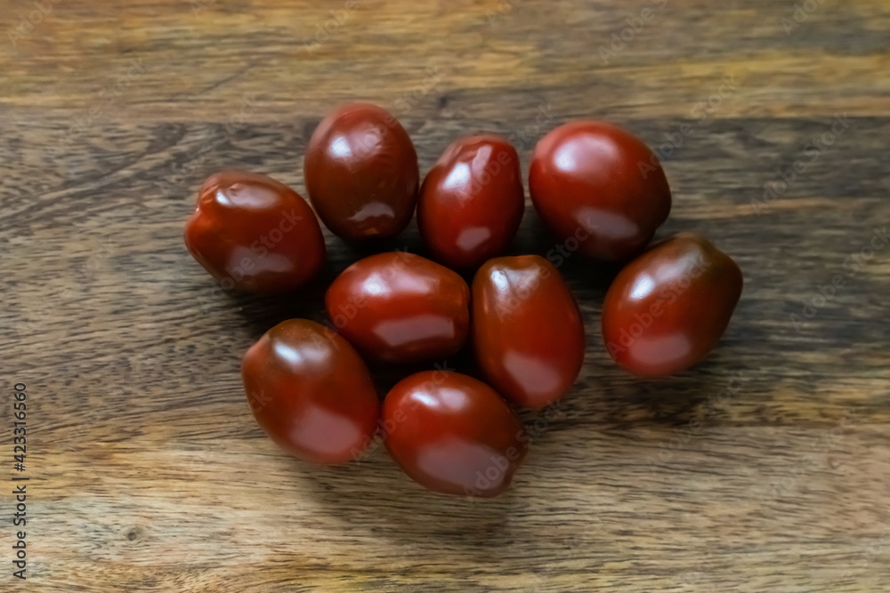 cherry tomatoes dark red burgundy sprinkled on a wooden background cherry tomatoes dark red burgundy sprinkled on a wooden background