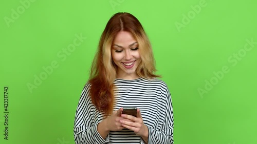 Young blonde teenager girl using mobile phone over isolated background. Green screen chroma key