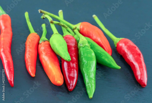 hot green and red chili peppers lie on a black background, small pods the base of shirachi sauce