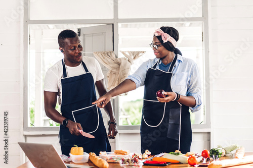 Portrait of love african american couple having fun cooking food together with fresh vegetable salad and sandwich ingredients to prepare the yummy eating in kitchen at home