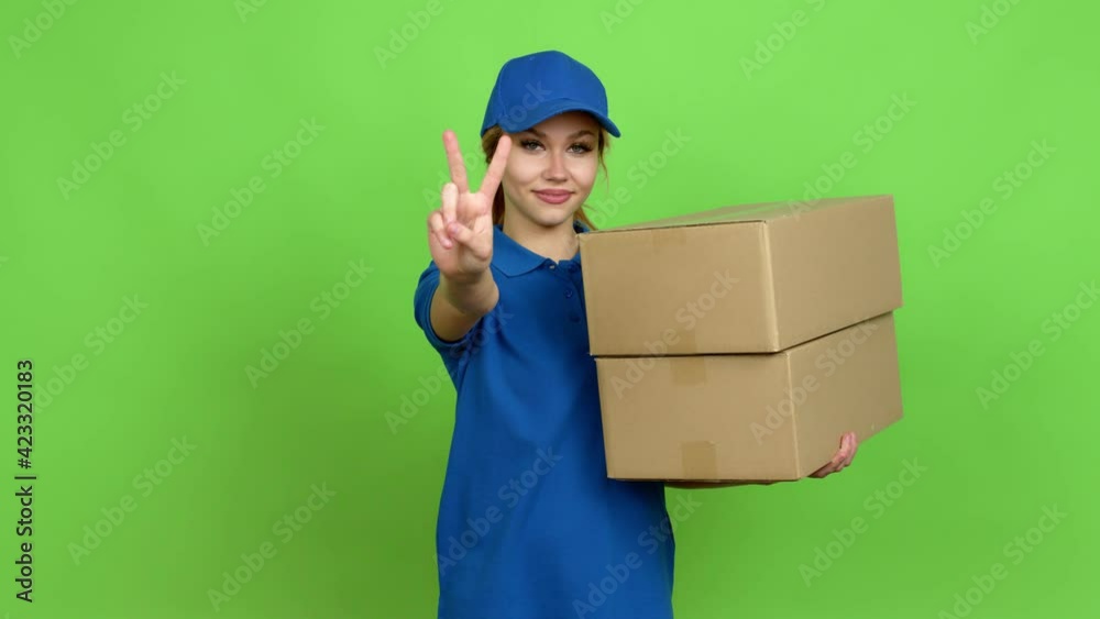 Young blonde teenager girl holding boxes for delivery happy and counting with fingers over isolated background. Green screen chroma key Young blonde teenager girl holding boxes for delivery happy and counting with fingers over isolated background. Green screen chroma key