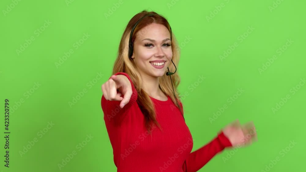 Young blonde teenager girl telemarketer points finger at you with a confident expression over isolated background. Green screen chroma key Young blonde teenager girl telemarketer points finger at you with a confident expression over isolated background. Green screen chroma key