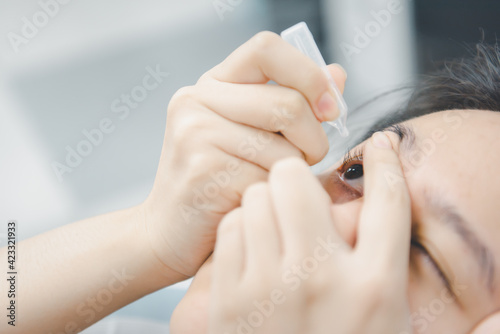 Woman use eye drop  artificial tears to the eye