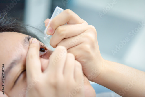 Woman use eye drop  artificial tears to the eye