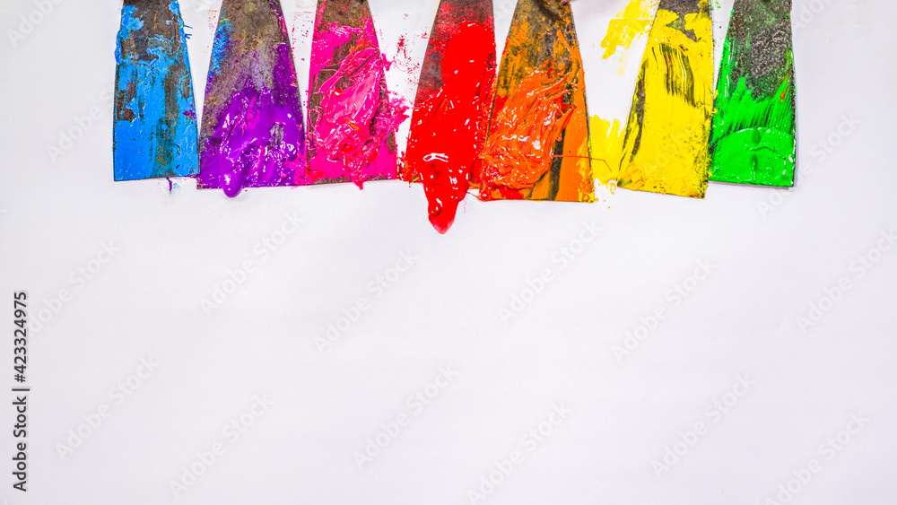 Naklejka premium blue ,purple, pink, red,orange, yellow and green are slowly dripping from color scoop handle..and slowly spread onto the white paper.