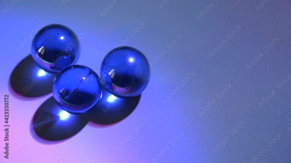 Moving glass marbles on white table children's game and moment of relaxation, multicolored light. Moving glass marbles on white table children's game and moment of relaxation, multicolored light.