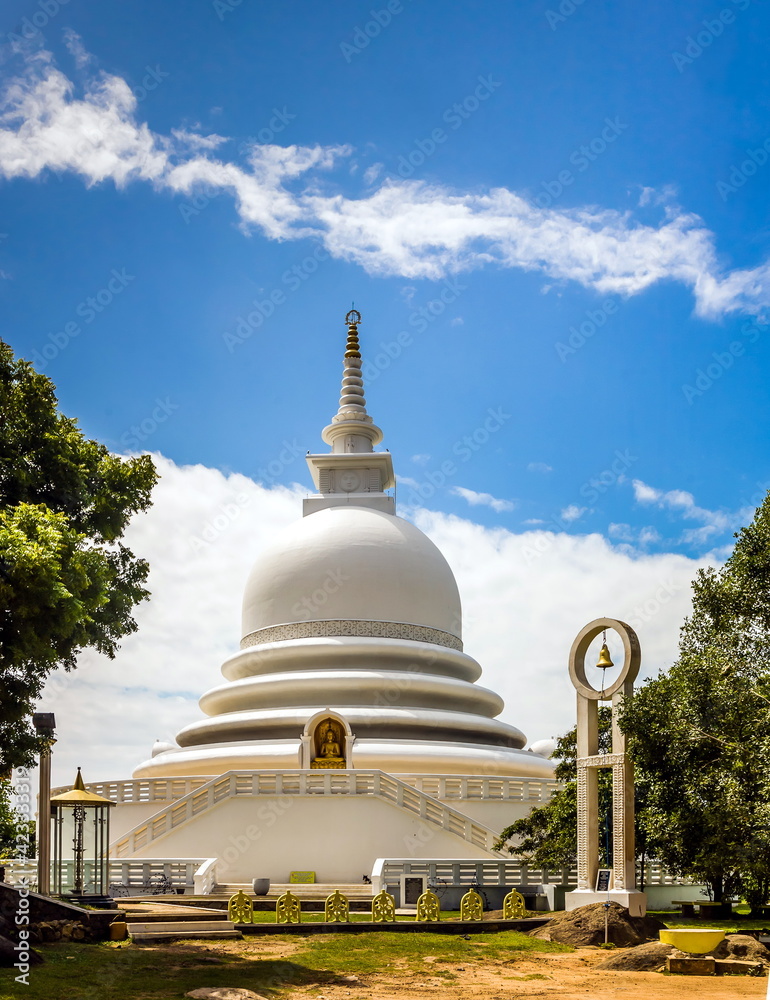 A religious building in Sri Lanka against the background of leafy trees and a blue sky with white clouds A religious building in Sri Lanka against the background of leafy trees and a blue sky with white clouds