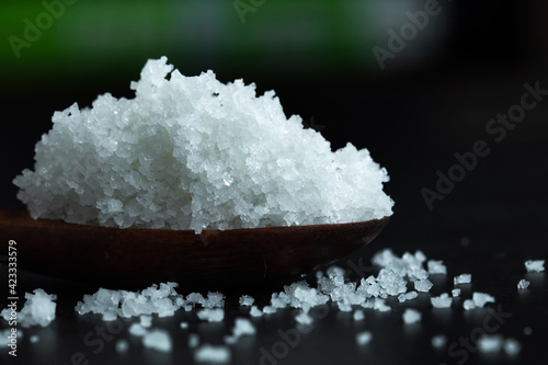 Flower of salt in wooden spoon on dark background. Selected focus.