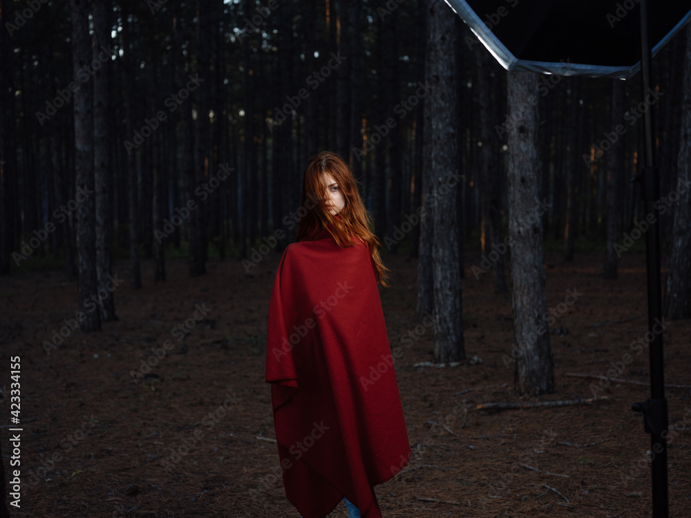 Beautiful woman with a red cape near the trees in the forest Beautiful woman with a red cape near the trees in the forest