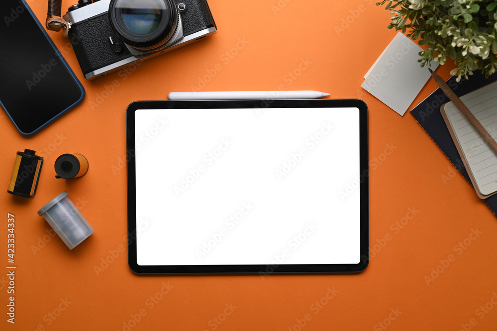 Top view of photographer workplace with digital tablet, camera, coffee cup and notebook on orange background. Top view of photographer workplace with digital tablet, camera, coffee cup and notebook on orange background.