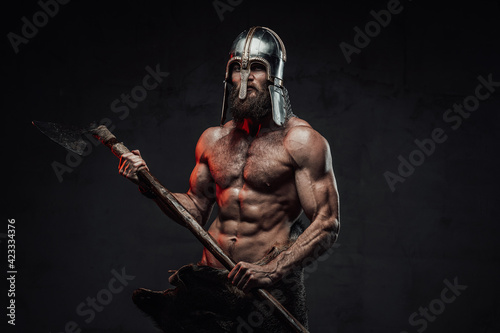 Viking with naked torso and beard posing in dark background