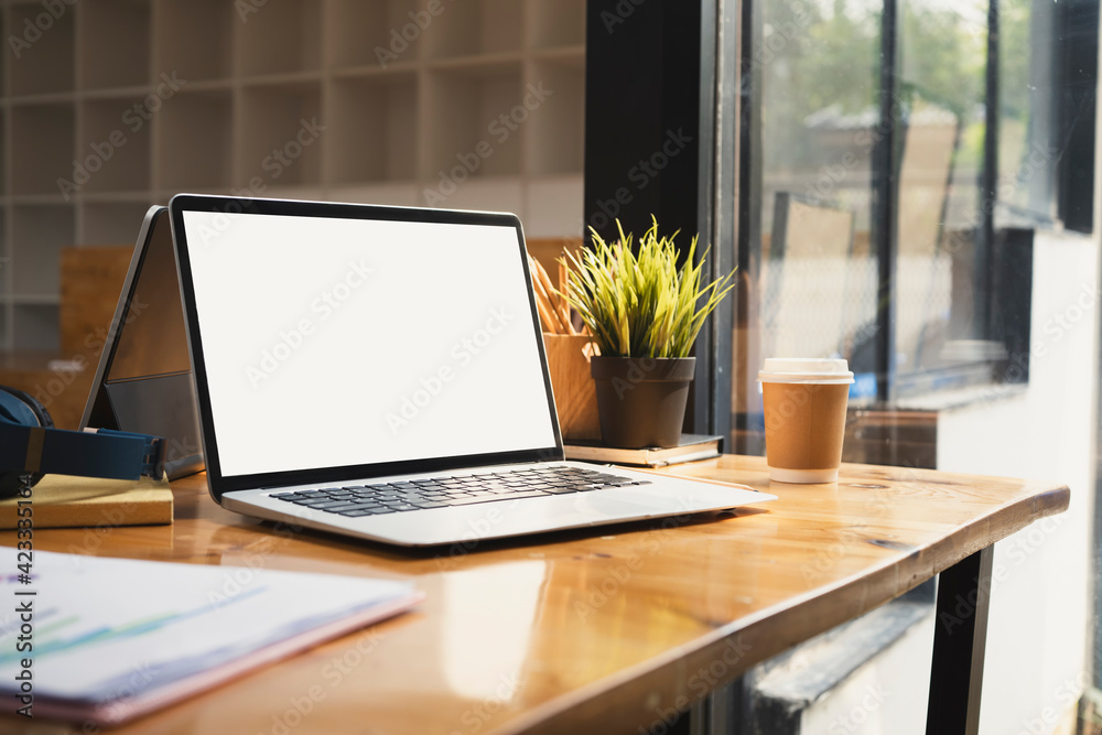 Computer laptop with white screen, coffee cup and document on wooden table. Computer laptop with white screen, coffee cup and document on wooden table.