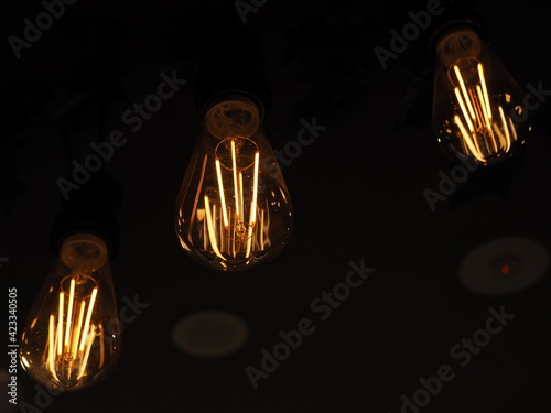 Three vintage light bulbs softly glowing with orange light  now very dim and about to die