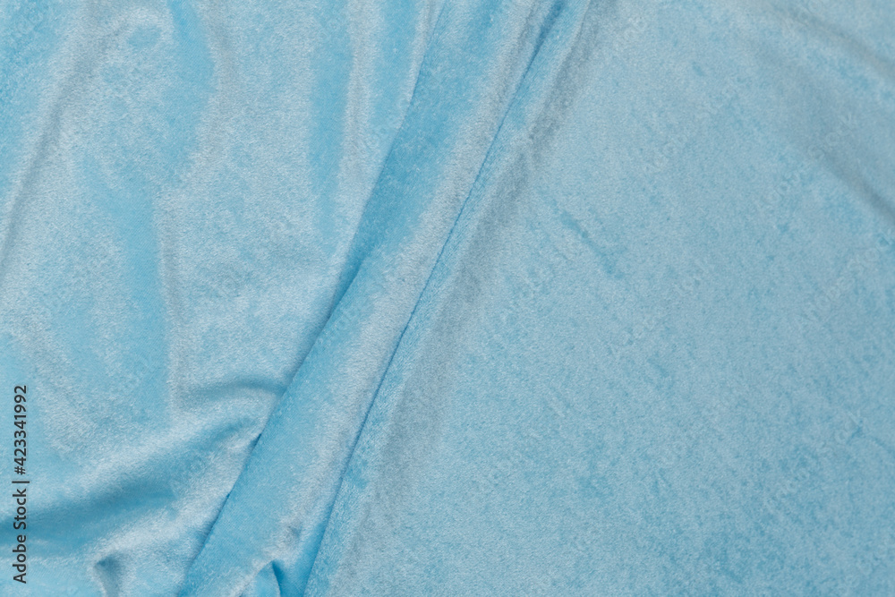 Colored blue textile satin fabric folded in folds and waves with highlights and texture Colored blue textile satin fabric folded in folds and waves with highlights and texture