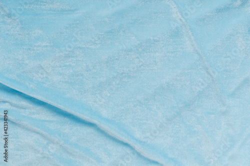 Colored blue textile satin fabric folded in folds and waves with highlights and texture