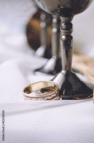 Gold ring on a white background with iron cups. Wedding Ring