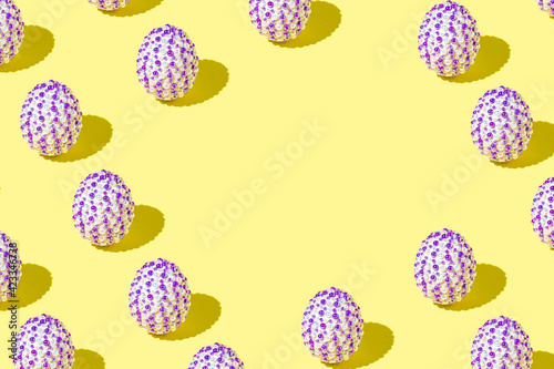 Creative Easter pattern made of natural white eggs with purple stickers on a yellow background. Minimal holiday or spring concept. Copy space.
