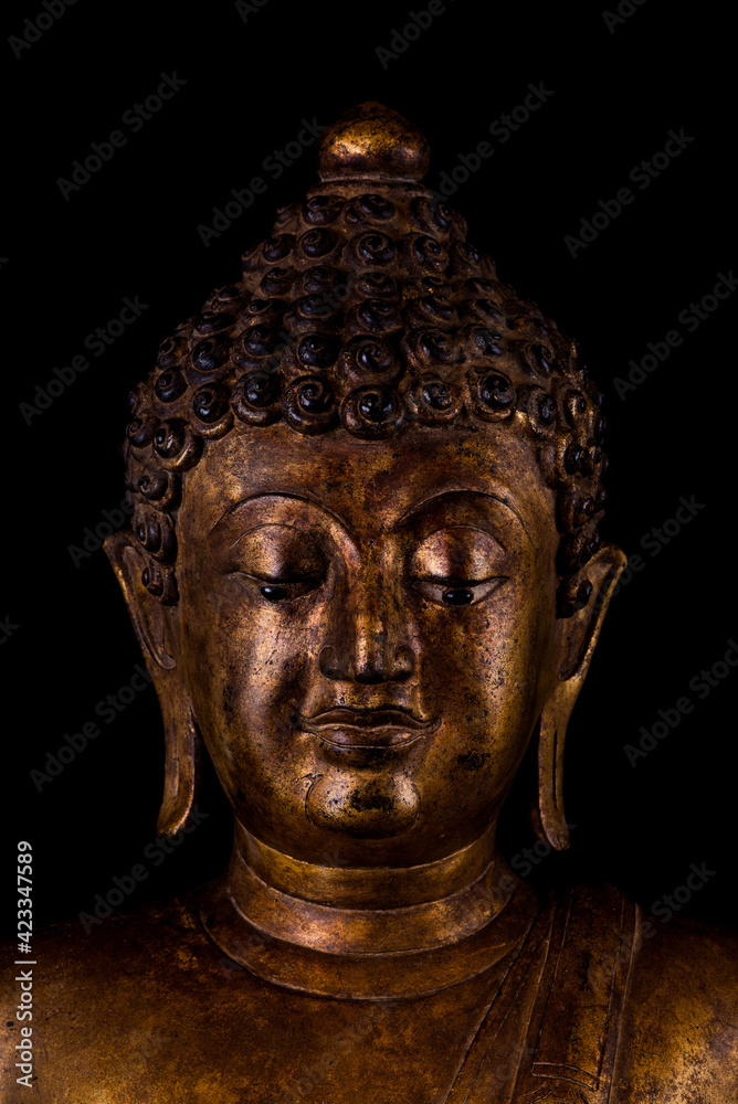 Portrait image close up of ancient art Buddhist statue isolated front side on isolated black background.