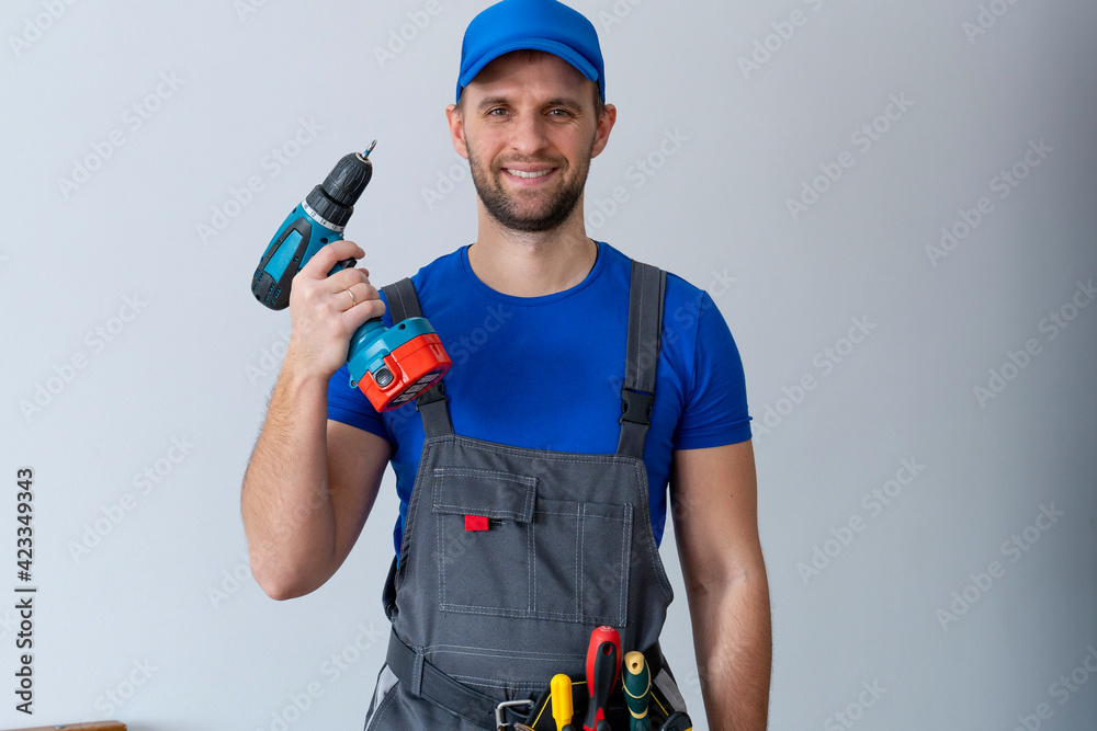 Uniformed maintenance worker holds a screwdriver and looks at the camera. Handyman wearing a tool belt Uniformed maintenance worker holds a screwdriver and looks at the camera. Handyman wearing a tool belt