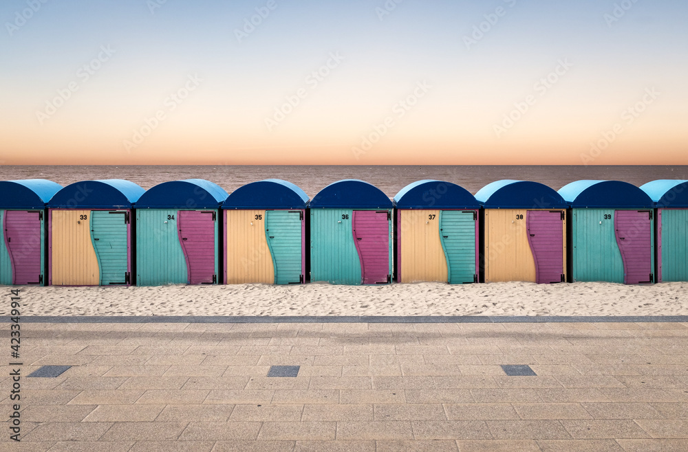 Row of vintage wooden beach huts against sunset sky