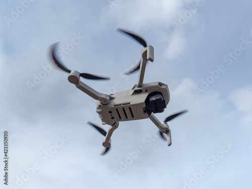 Grey drone with camera flying in the air outdoors. Little drone flying outside in sky.