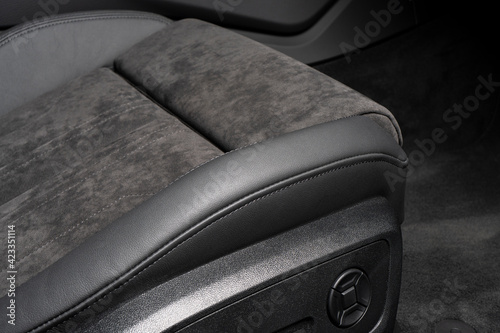 Modern luxury car black leather and alcantara interior. Part of black perforated leather car seat details with white stitching. Interior of prestige car. Comfortable perforated leather seats.