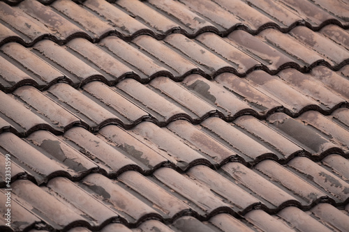 ribbed tiled roof old and weathered closeup background dark brown © Kai Beercrafter