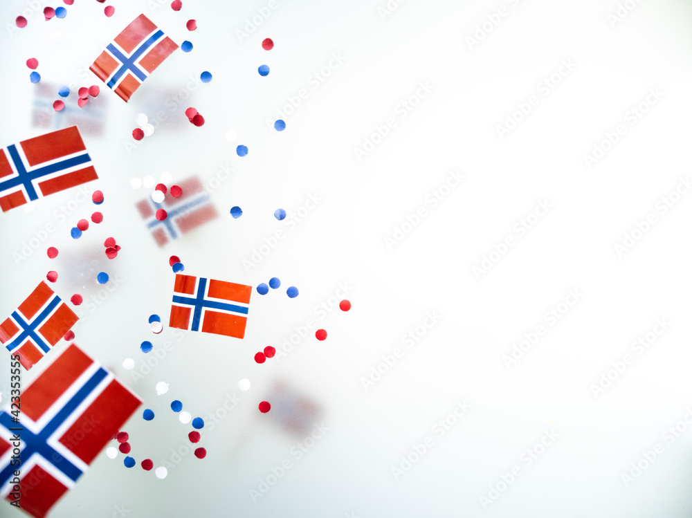 Obraz premium Norwegian independence day, Constitution day, may 17. holiday of freedom, victory and memory. concept of patriotism and faith. paper confetti and mini flags on white foggy background 