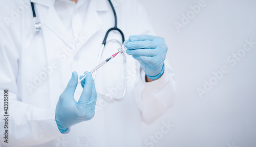 Doctor or scientist with a stethoscope holding COVID-19 vaccine, measles, coronavirus vaccine shot for diseases outbreak vaccination, vaccine Concept fight against virus covid-19 corona virus