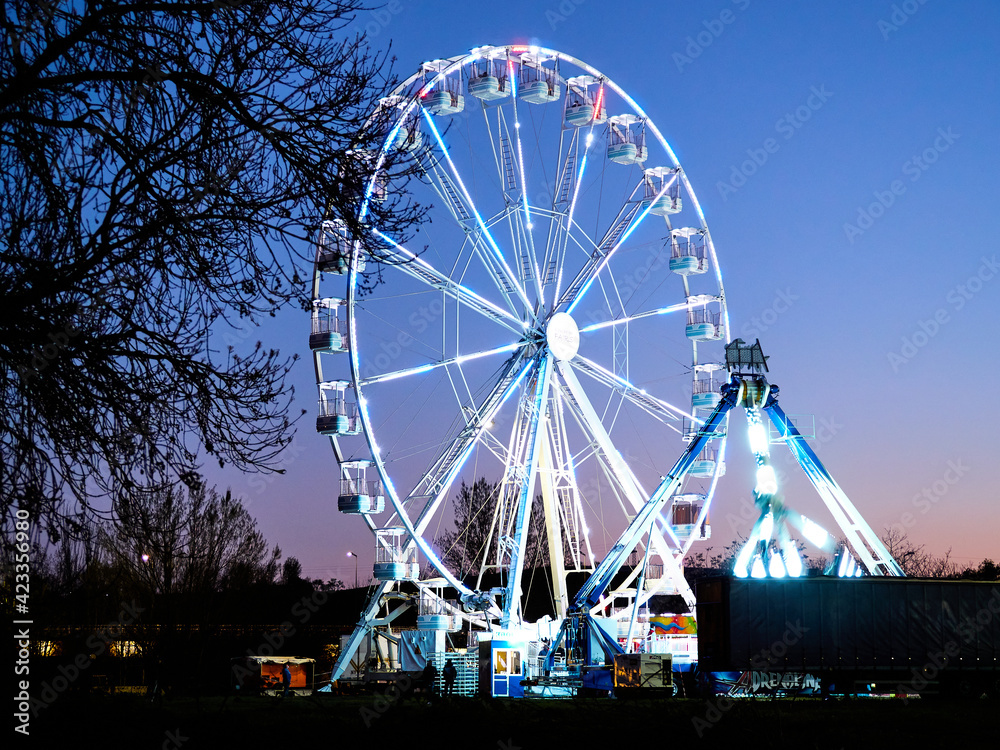 Ferris wheel and amusement park at dusk, at night.