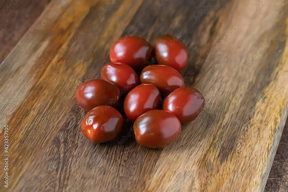 dark red tomato sprinkled on a brown wooden background dark red tomato sprinkled on a brown wooden background
