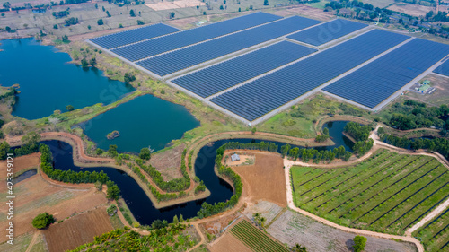 Solar panels farm between agriculture fields in aerial view.