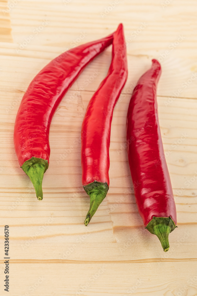 three chili peppers red fresh vegetable long pods on wooden background three chili peppers red fresh vegetable long pods on wooden background