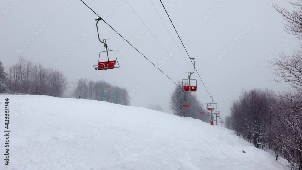 View of the colored lift against the background of a mountain spruce forest and gray sky in the beautiful Carpathians View of the colored lift against the background of a mountain spruce forest and gray sky in the beautiful Carpathians